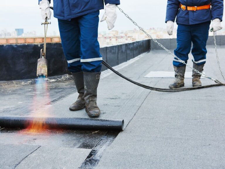 Werknemers installeren dakbedekking met een brander.