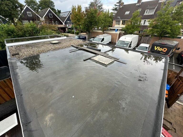 Waterdicht plat dak met geparkeerde auto's op oprit.