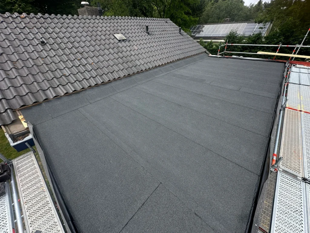 Afgewerkt plat dak met bitumen tussen schuine pannendaken in Westzaan