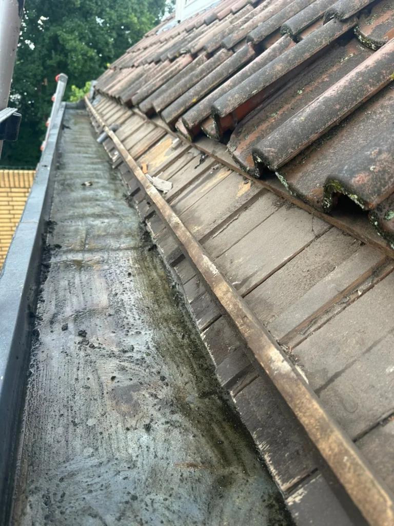 Oude goot met vuil en aanslag onder een pannendak in Westzaan