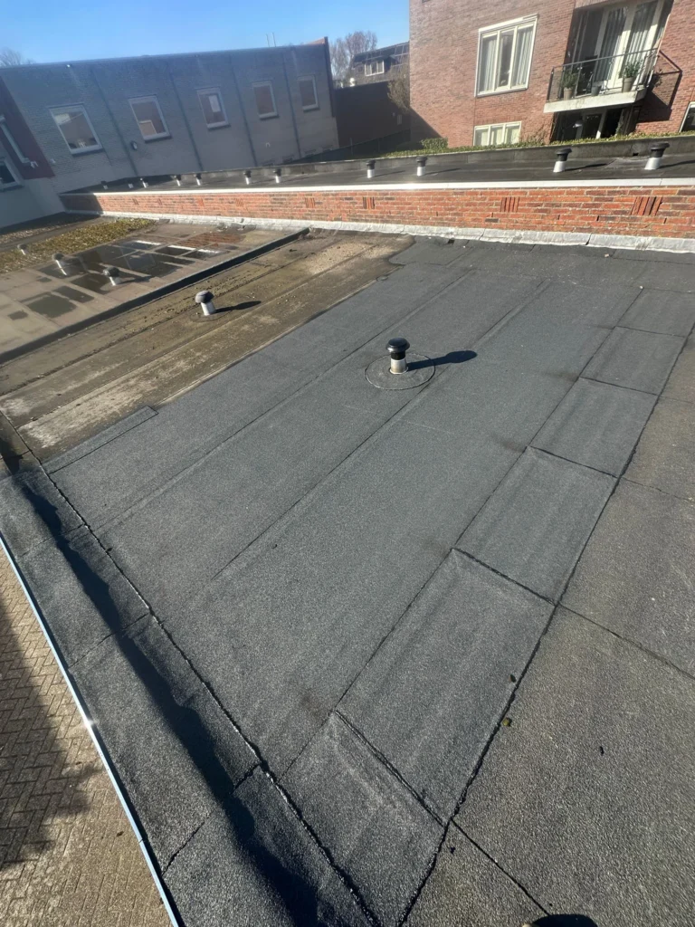 Plat garagedak waarvan een deel al nieuwe dakbedekking heeft in Westzaan