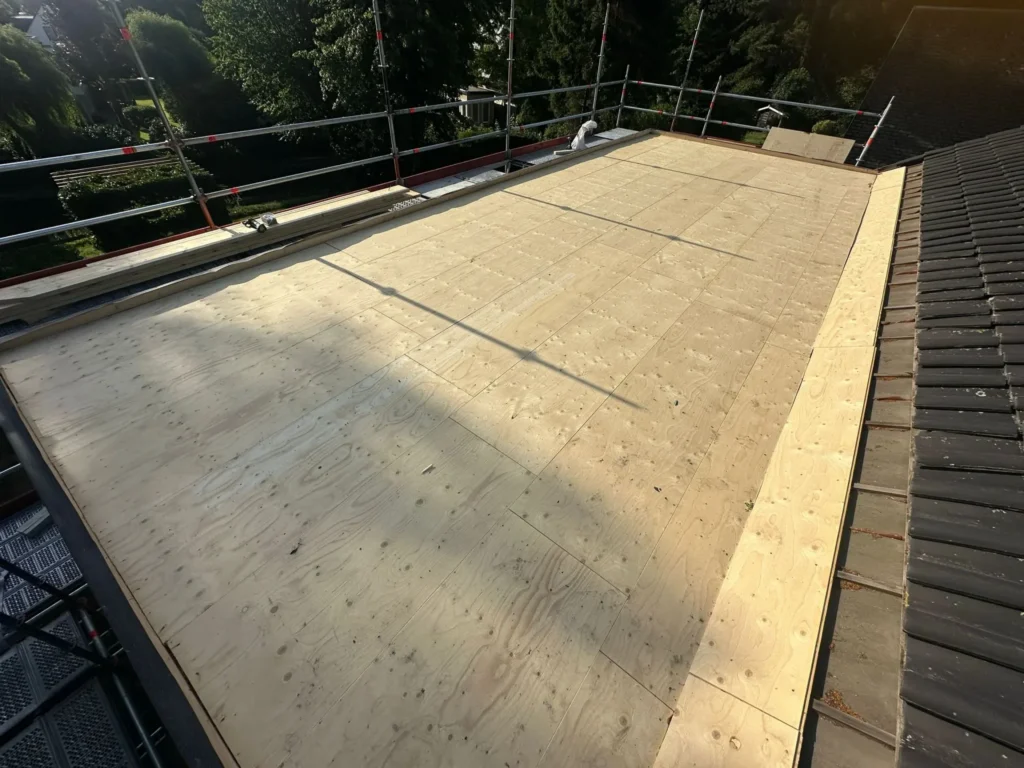 Nieuw houten dakbeschot op een plat dak naast een pannendak in Westzaan