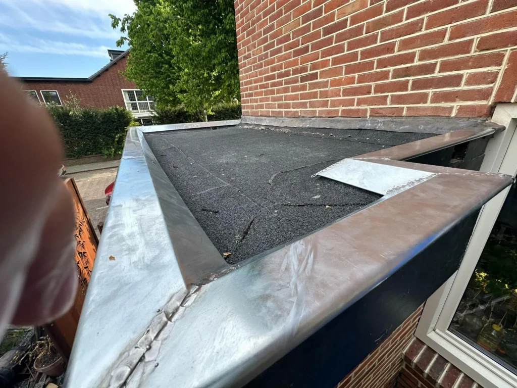 Nieuwe zinken hoek van een dakrand op een plat dak in Westzaan