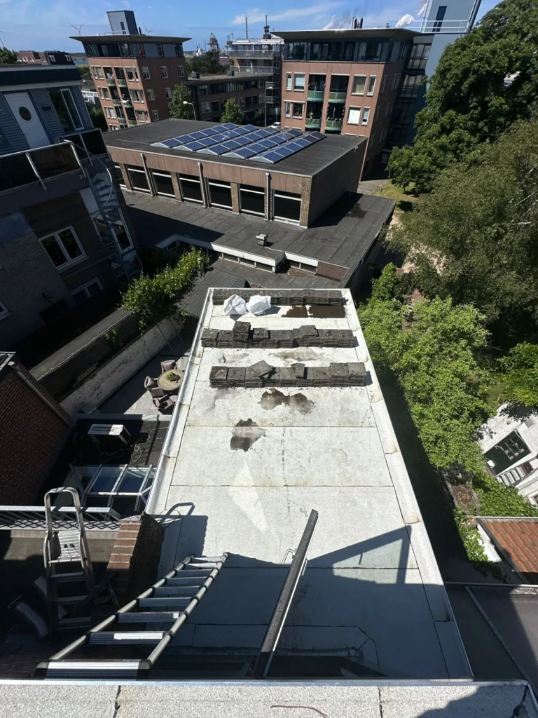Smal plat dak met lichte dakbedekking en losse materialen in Westzaan